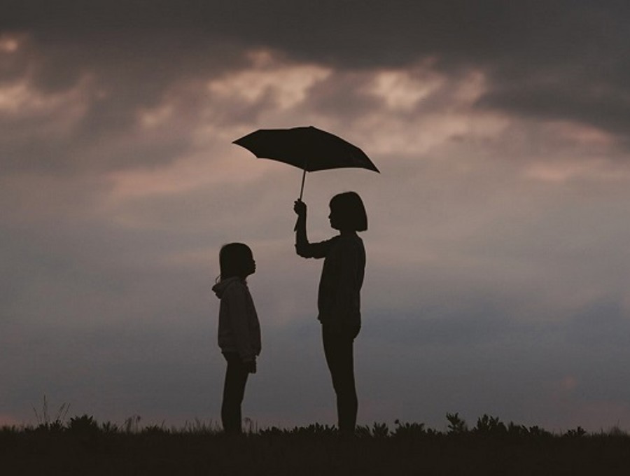 Two children standing outside holding an umbrella.